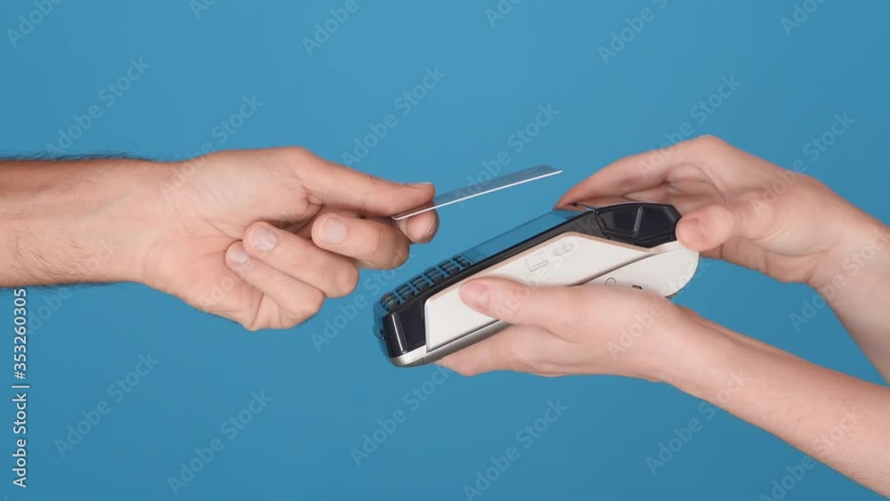 Close up hands of cashier holding credit card reader and client paying trought contactless credit card. Man paying bill mobile phone with NFC technology isolated on lightblue background, copy space Close up hands of cashier holding credit card reader and client paying trought contactless credit card. Man paying bill mobile phone with NFC technology isolated on lightblue background, copy space