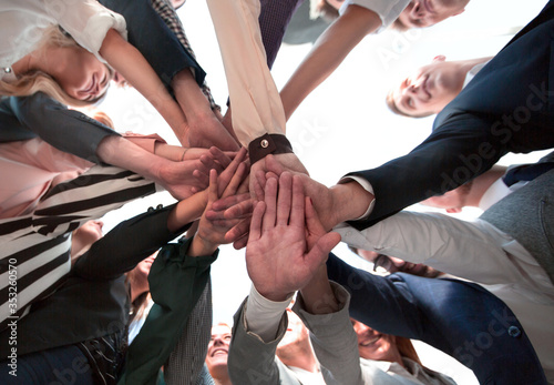 group of diverse young people folding their hands in a circle
