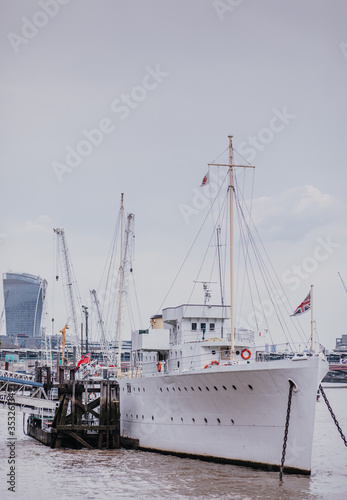 beautiful white ship parked on the river Thames, bright sky above the river. Walkie Talkie building in the background. white metal ship with masts © Vitalie