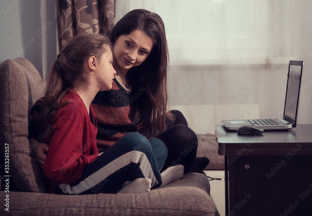 Happy smiling woman working at home on computer and cute kid studying in mobile phone. Family sitting on sofa together near each other. Stay home concept, covid-19, quarantine. Closeup Happy smiling woman working at home on computer and cute kid studying in mobile phone. Family sitting on sofa together near each other. Stay home concept, covid-19, quarantine. Closeup