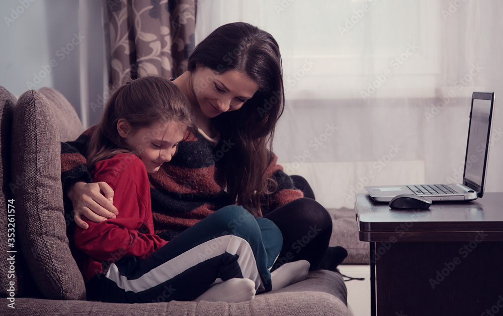 Happy smiling woman working at home on computer and cute kid studing in mobile phone. Family sitting on sofa together near each other. Stay home concept, covid-19, quarantine. Closeup portrait Happy smiling woman working at home on computer and cute kid studing in mobile phone. Family sitting on sofa together near each other. Stay home concept, covid-19, quarantine. Closeup portrait