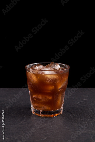 Iced coffee in a transparent glass on a dark background with copy space. Cold summer drink