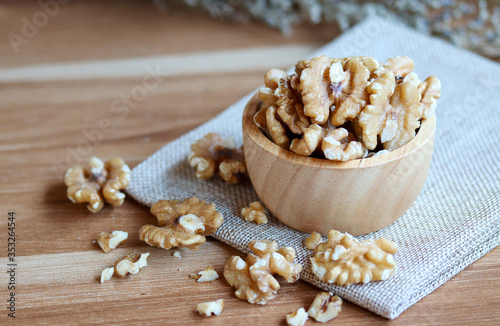 Whole walnuts in wooden bowl on table.
