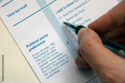 Closeup hand with pen hovering over party choices on a Voter Registration form