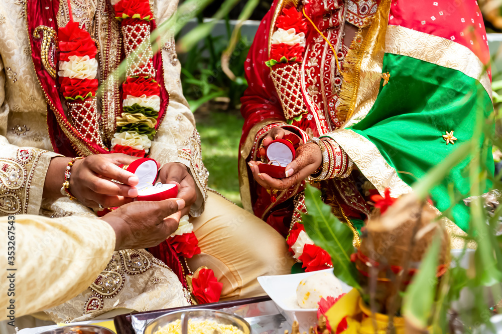 Indian bride and groom in colorful ritual clothes exchanging wedding rings  during traditional hindu wedding marriage ceremony
