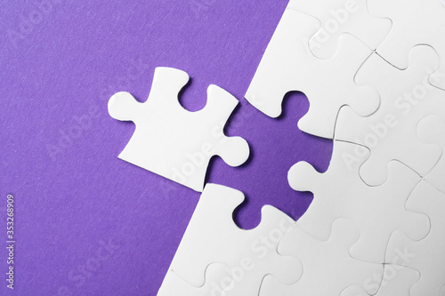 White puzzle with unfitting piece on purple background, flat lay
