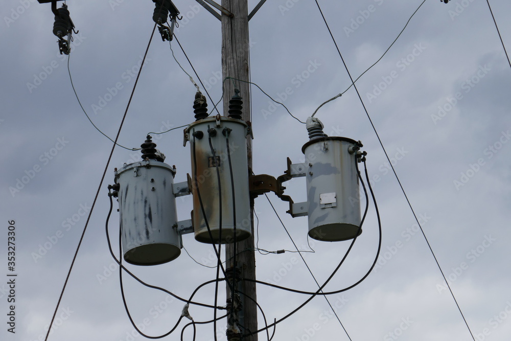 Telephone pole capacitors close-up against cloudy sky Telephone pole capacitors close-up against cloudy sky