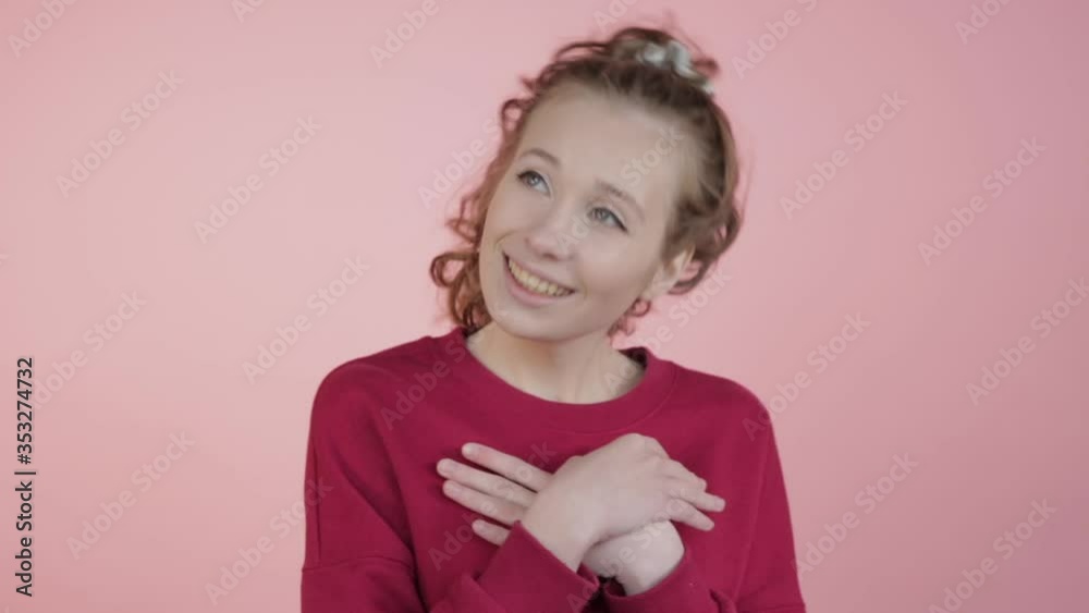 A happy girl with wavy hair dreams and put her hands on her chest. A happy girl with wavy hair dreams and put her hands on her chest.
