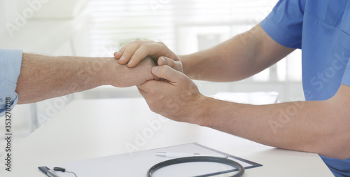 Doctor holding senior patient s hand in office  closeup. Banner design