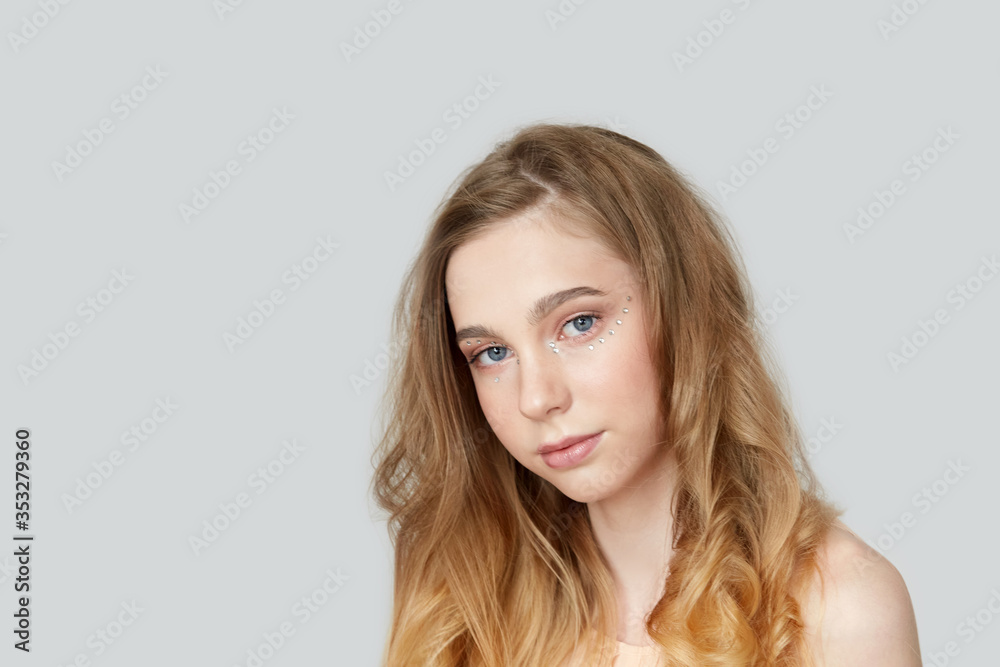 Portrait of a beautiful young girl with bright wavy hair. Blonde