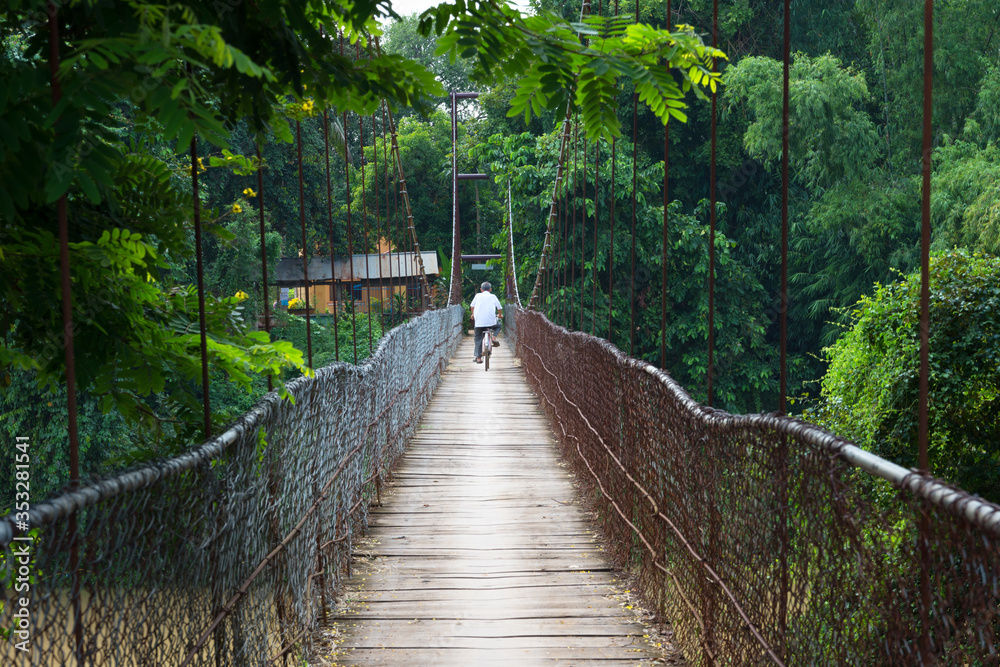 Fototapeta premium An unidentified man is crossing the bridge with a bicycle.