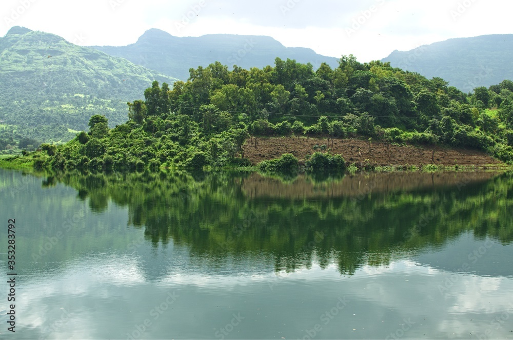 Fototapeta premium Reflection of a hill covered with green trees
