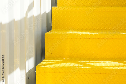 Yellow metal modern stairs and white corrugated wall.