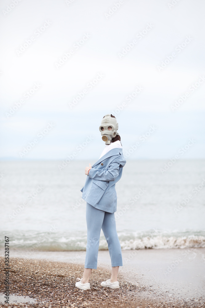 Portrait of girl in gas mask on the beach. 
Quarantine summer 2020. Fashion 2020.