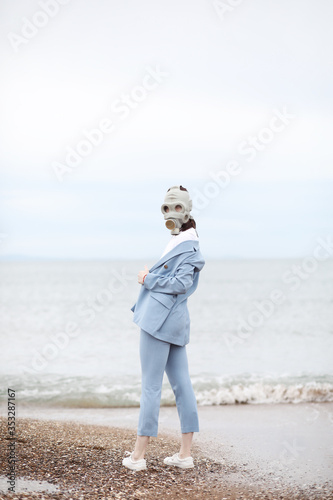 Portrait of girl in gas mask on the beach. 
Quarantine summer 2020. Fashion 2020. photo
