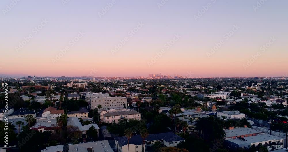 Aerial drone view tracking backwards, fast in reverse, away from downtown Los Angeles during dusk after the vivid rainbow sunset. low hanging just above rooftops, in LA, California, America Aerial drone view tracking backwards, fast in reverse, away from downtown Los Angeles during dusk after the vivid rainbow sunset. low hanging just above rooftops, in LA, California, America