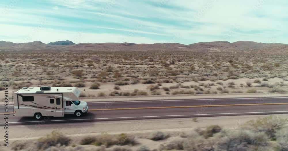 AERIAL - A drone follows an RV that drives at high speed through the image from left through right in the Mojave Desert on a sunny day AERIAL - A drone follows an RV that drives at high speed through the image from left through right in the Mojave Desert on a sunny day