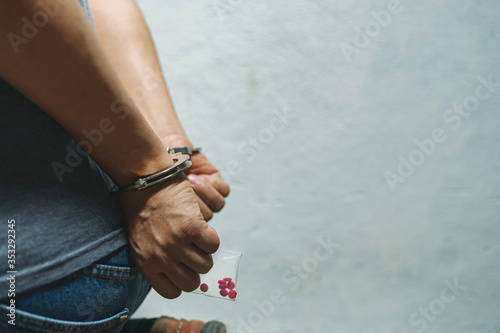 Drug dealer under arrest confined with handcuffs and hands, sale of drugs is punishable by law.