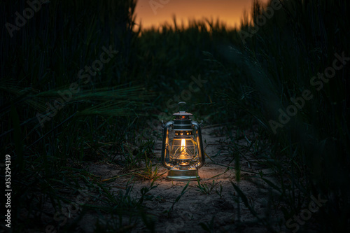 burning lantern stands in a cornfield at dusk