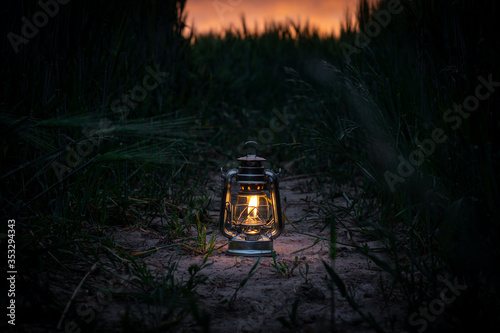 burning lantern stands in a cornfield at dusk