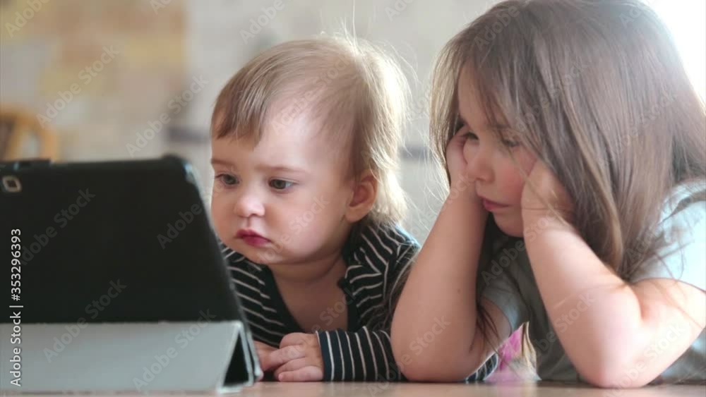 the kids are watching cartoons on the tablet. Family time, vacation. The concept of homework, quarantine, self-isolation, protection from coronavirus, virus, home education, distance work, training the kids are watching cartoons on the tablet. Family time, vacation. The concept of homework, quarantine, self-isolation, protection from coronavirus, virus, home education, distance work, training
