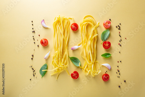 Overhead view of Homemade pasta and cherry tomatoes on yellow surface