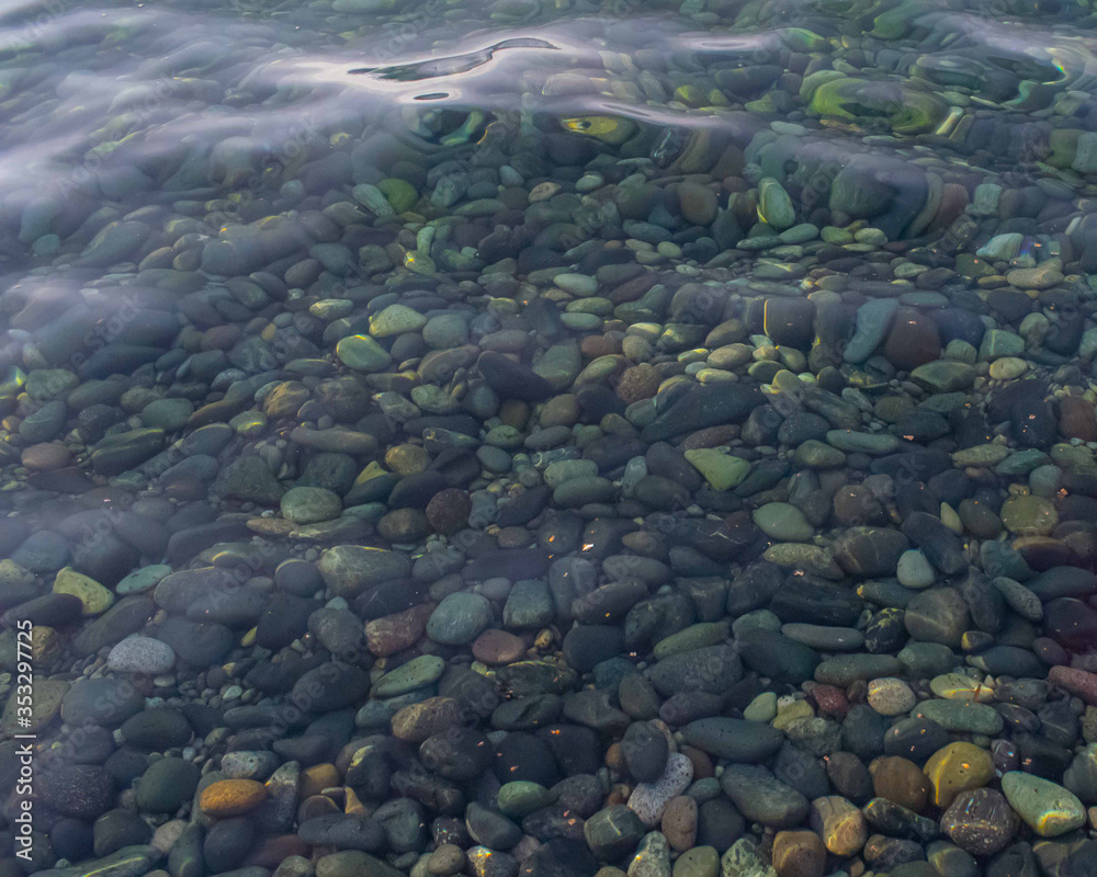 A clear water with smooth pebble stones under the water. Ocean water