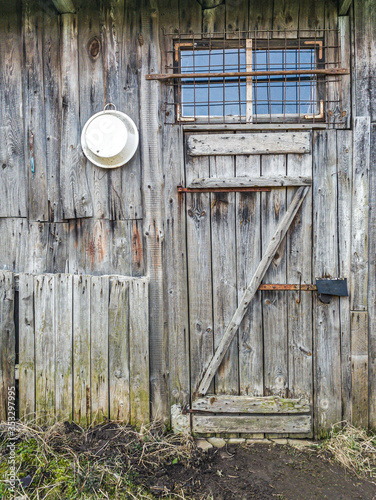 old weathered wooden shed wall with closed door and window