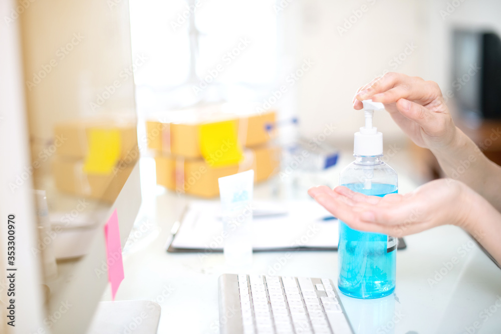 Close up of business woman wash hand with  sanitizer gel. Work from home with computer for communication during quarantine period of pandemic corona virus or covid-19