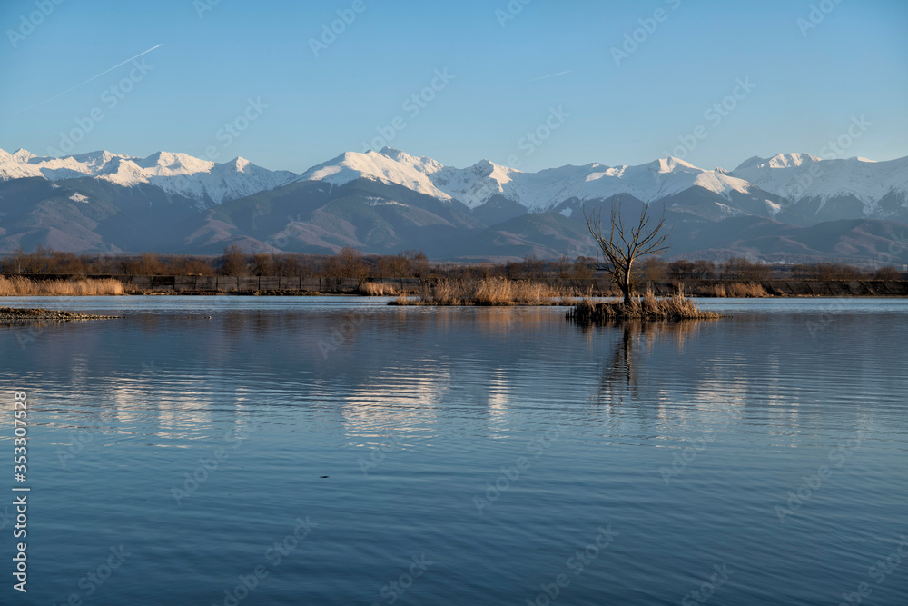 Carpathian mountain range landscapes with mountain peakc covered in snow. Mountain string reflection in blue water