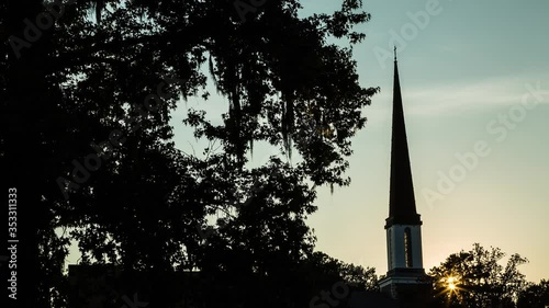 Time lapse of the sun setting behind a church steeple. photo