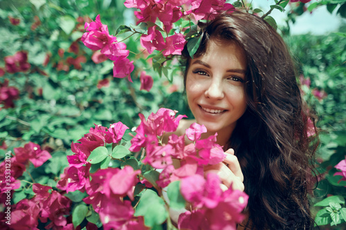 Close up portrait girl in the park on a background of pink flowers 