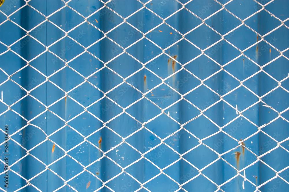 wire mesh fance in front of blue corrugate metal container