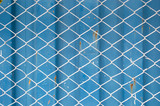 wire mesh fance in front of blue corrugate metal container