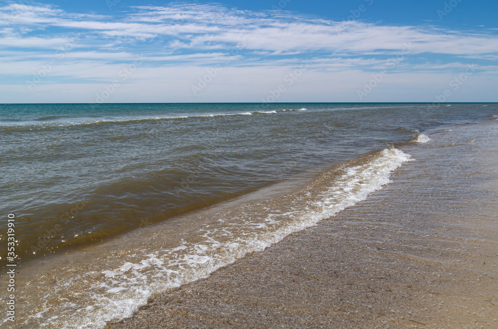 A small calm breaking sea wave on a sandy beach on a desert island in the Black Sea.