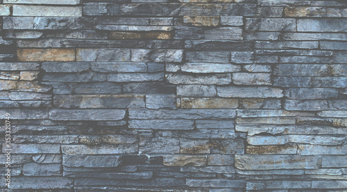 Art technique design of unshaped Gray stone wall pattern.Stone cladding wall made of striped stacked slabs for background.