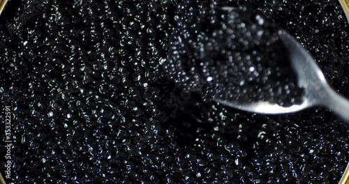 Spoon stirred black caviar. Macro background.