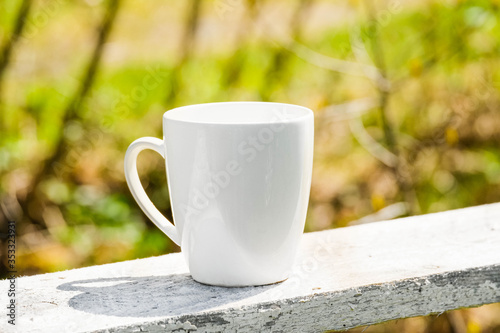White coffee mug mock up outdoor with blurred background. Tea mug mockup for branding, template, logo, nature blurred background at summer terrace. White cup mock up, cappuccino mug mock-up outdoor.