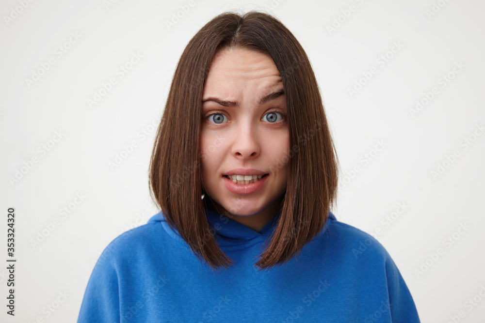 Portrair of young lovely short haired blue-eyed woman without makeup raising confusedly eyebrow while looking at camera, isolated over white background Portrair of young lovely short haired blue-eyed woman without makeup raising confusedly eyebrow while looking at camera, isolated over white background
