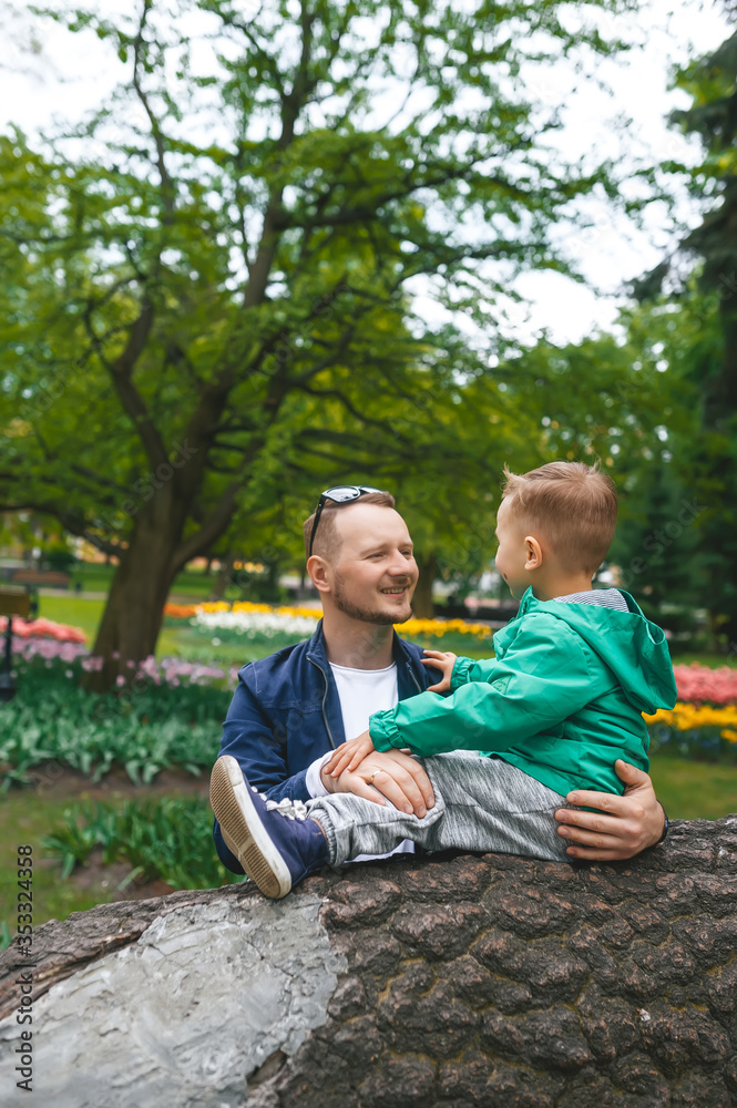 Happy dad having fun his little cute son on a log tree in the park. Happy dad having fun his little cute son on a log tree in the park.