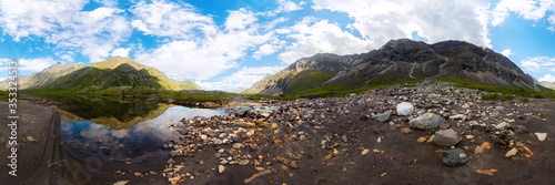 Transparent clear water of a mountain lake under a blue sky in the clouds. sand beach. cylindrical panorama 360