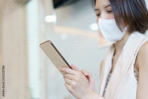 Woman wearing protective mask using smart phone.