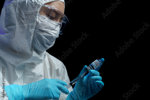 Woman in hazmat suit with vaccine and syringe injection for prevention, immunization and treatment from corona virus infection.