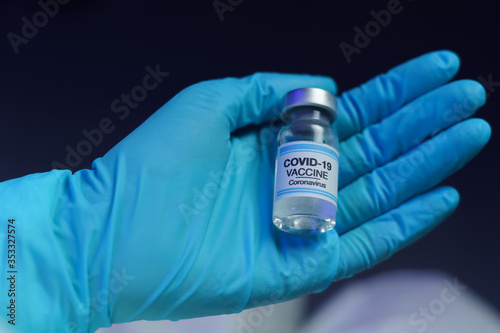 Hand in blue glove holding vaccine and syringe injection for prevention, immunization and treatment from corona virus infection.