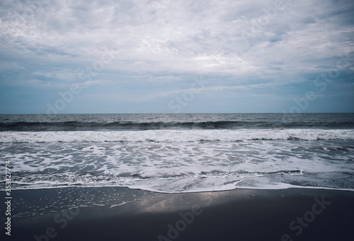 Small wavess on the beach with black sand. West Sumatra, Indonesia