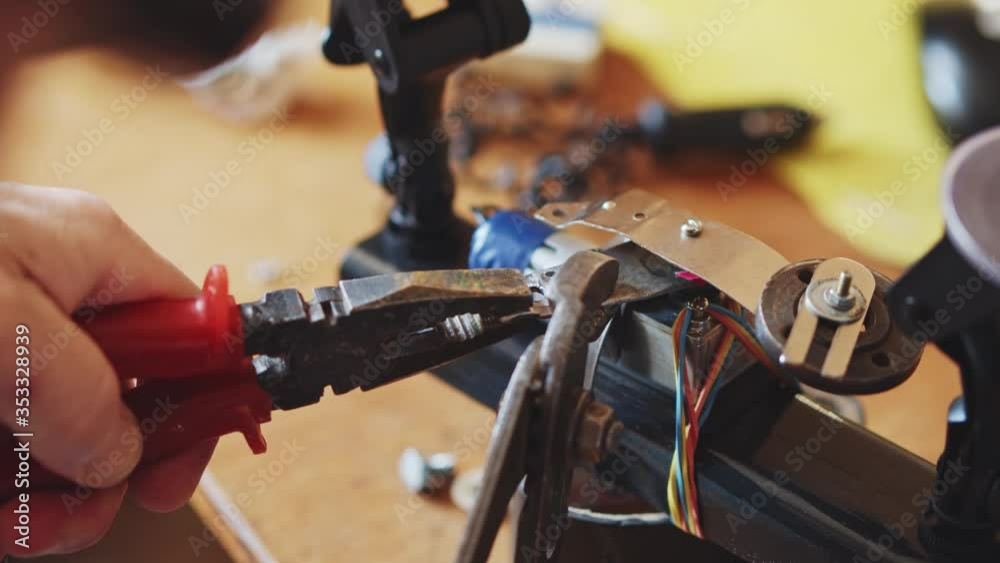 Close-up shot of mature man in a workshop repairing drone copter stuck motor improving and fixing details. Concept of busyness, hard work, concentration. Close-up shot of mature man in a workshop repairing drone copter stuck motor improving and fixing details. Concept of busyness, hard work, concentration.