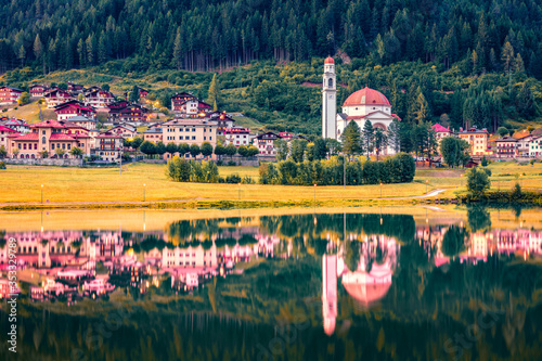 Beautiful morning view of Parrocchia di San Lucano Vescovo Catholic Church. Calm summer scene of Santa Caterina lake and Auronzo di Cadore resort, Italy, Europe. Traveling concept background. photo