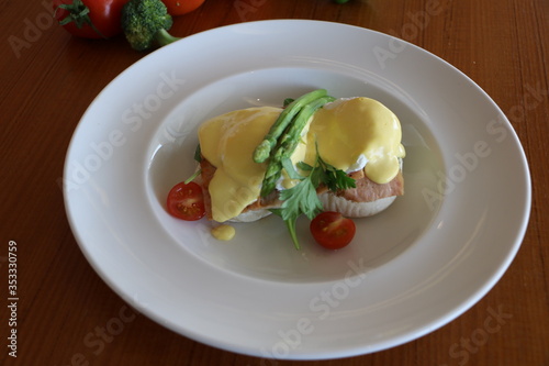 Eggs benedicts, Poached eggs on brioche bun, turkey bacon, asparagus and top with hollandaise sauce