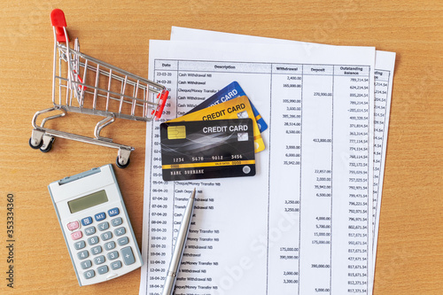 Credit cards and Cart supermarket and Calculator on Bank statement on a Wooden table