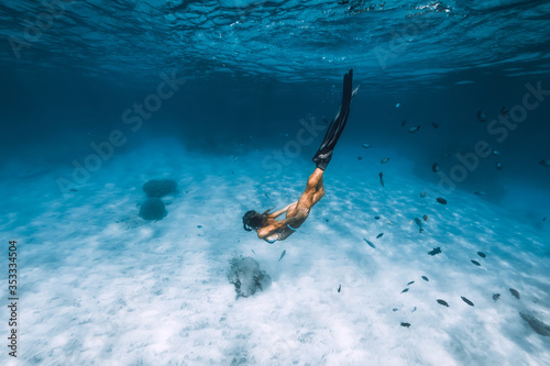 Freediver girl in bikini with fins glides underwater in blue transparent sea © artifirsov